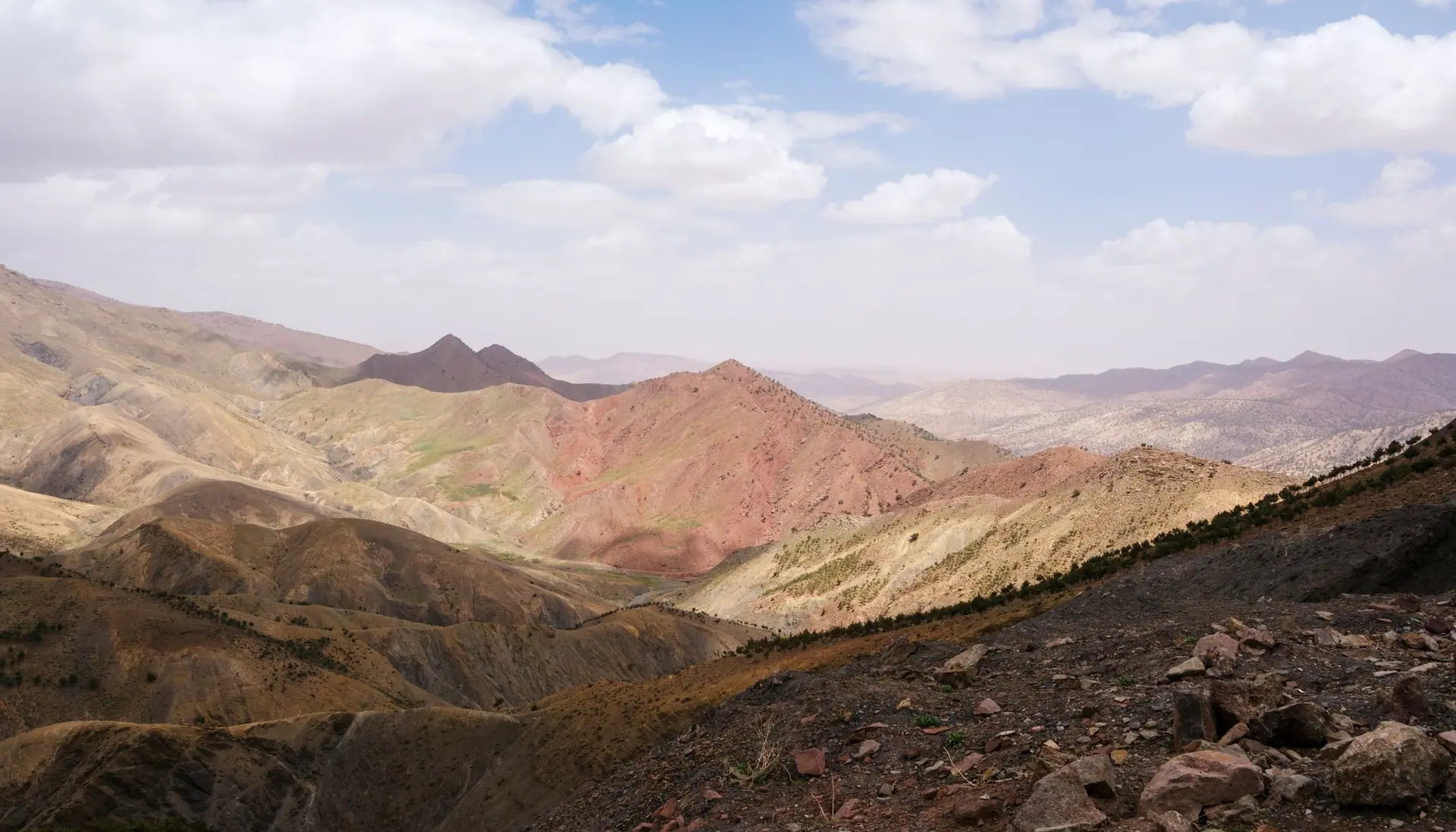 A stunning landscape of the Atlas Mountains under a partly cloudy sky in Morocco.