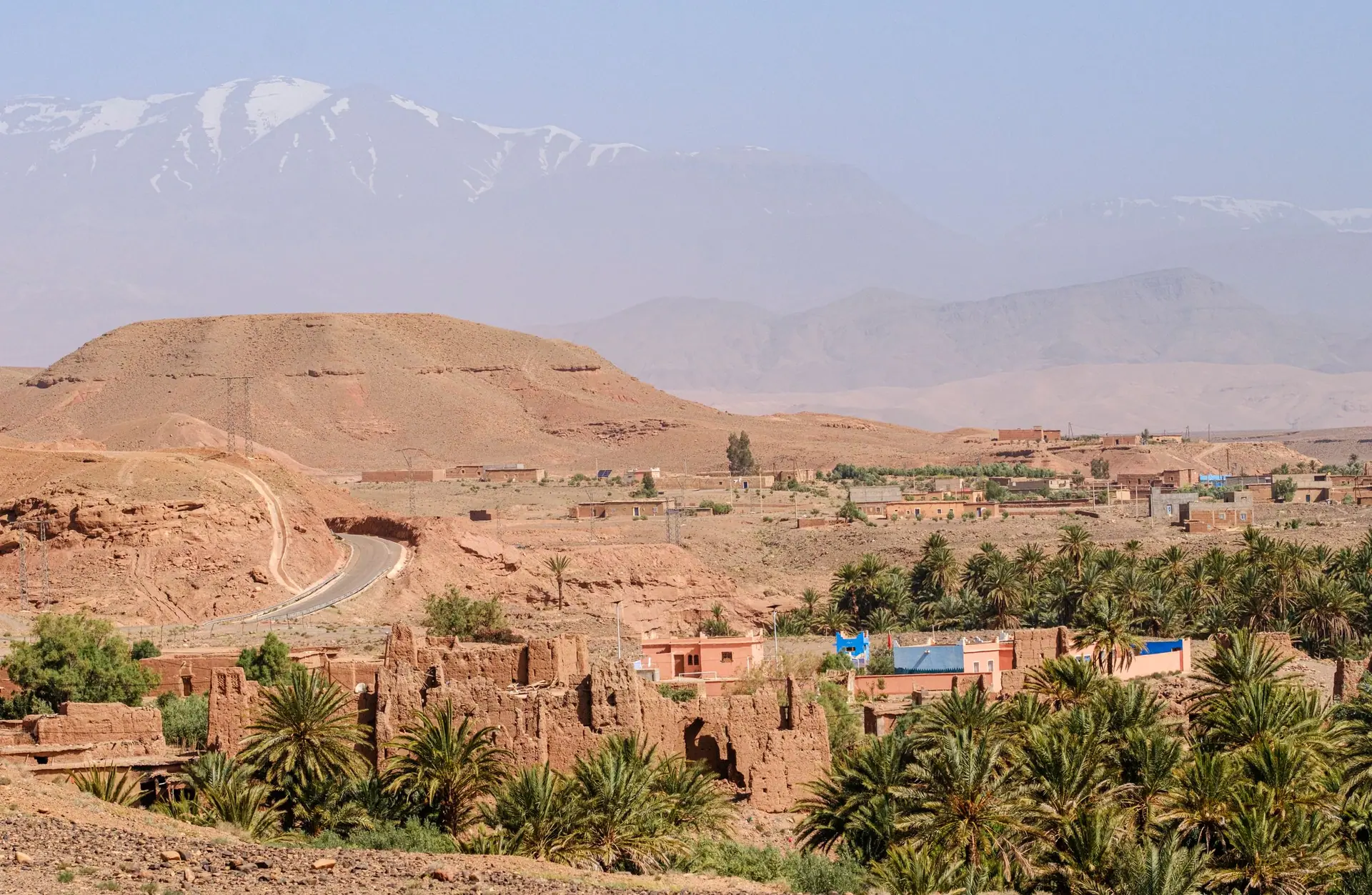 Picturesque view of Moroccan landscape with Atlas Mountains and palm trees.