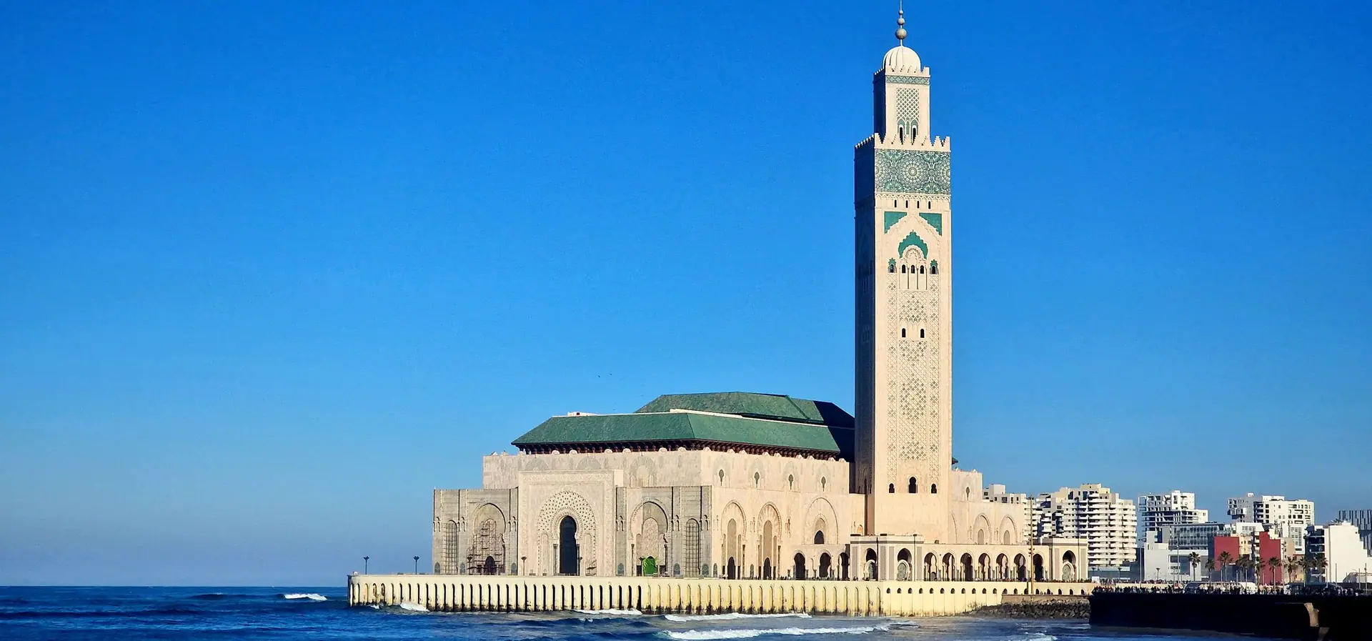 The majestic Hassan II Mosque in Casablanca with a vibrant blue sky background.