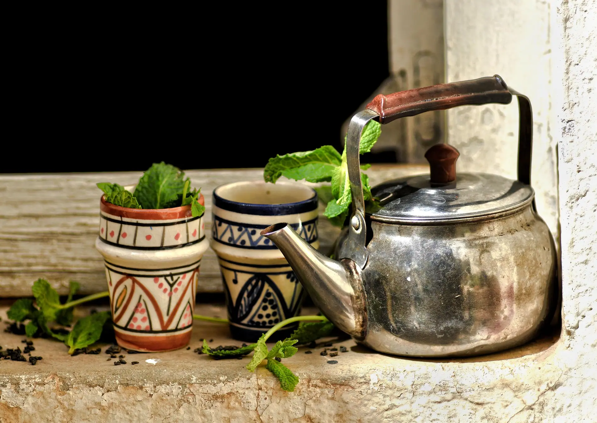Authentic Moroccan tea scene featuring a teapot and traditional cups with fresh mint leaves.