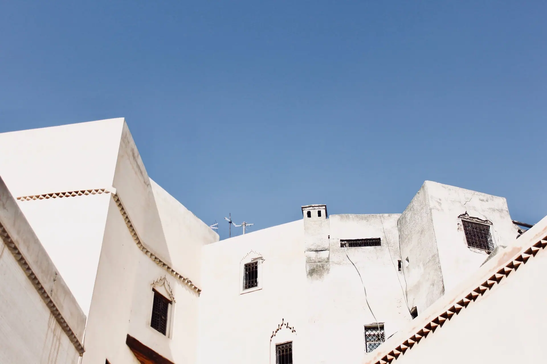 White buildings against a clear blue sky in the historic city of Fès, Morocco.
