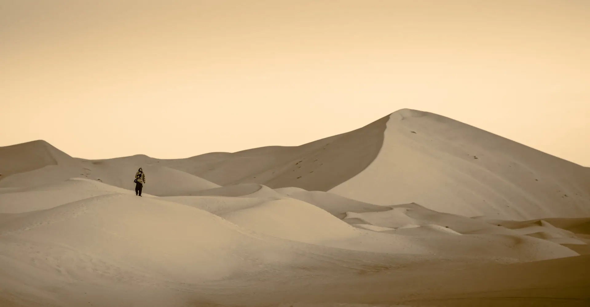 A lone traveler walks across the majestic dunes of Merzouga, Morocco, capturing solitude and adventure.
